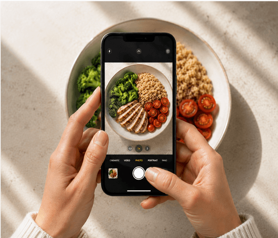 Hands photographing a plate of food with an iPhone in the Cibo app